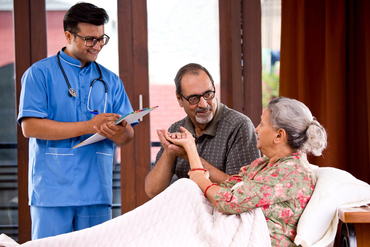 Male nurse making a note of senior patient at home